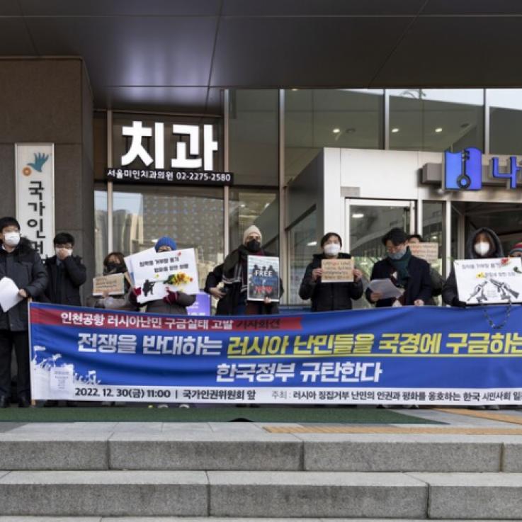 People holding a banner in front of an airport